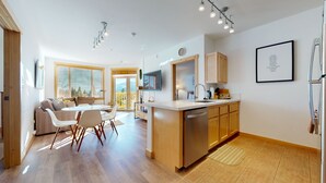 Una cocina moderna con armarios de madera, una isla central y un comedor con mesa y sillas.