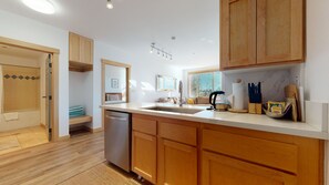Kitchen features a dishwasher, stainless steel sink, and a window with blinds.