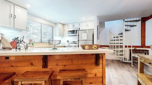 Een moderne keuken met witte kasten, een houten eiland en een roestvrijstalen koelkast.