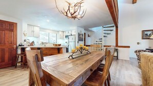 Een ruime keuken met een houten eettafel, een kroonluchter en een trap naar een hoger niveau.