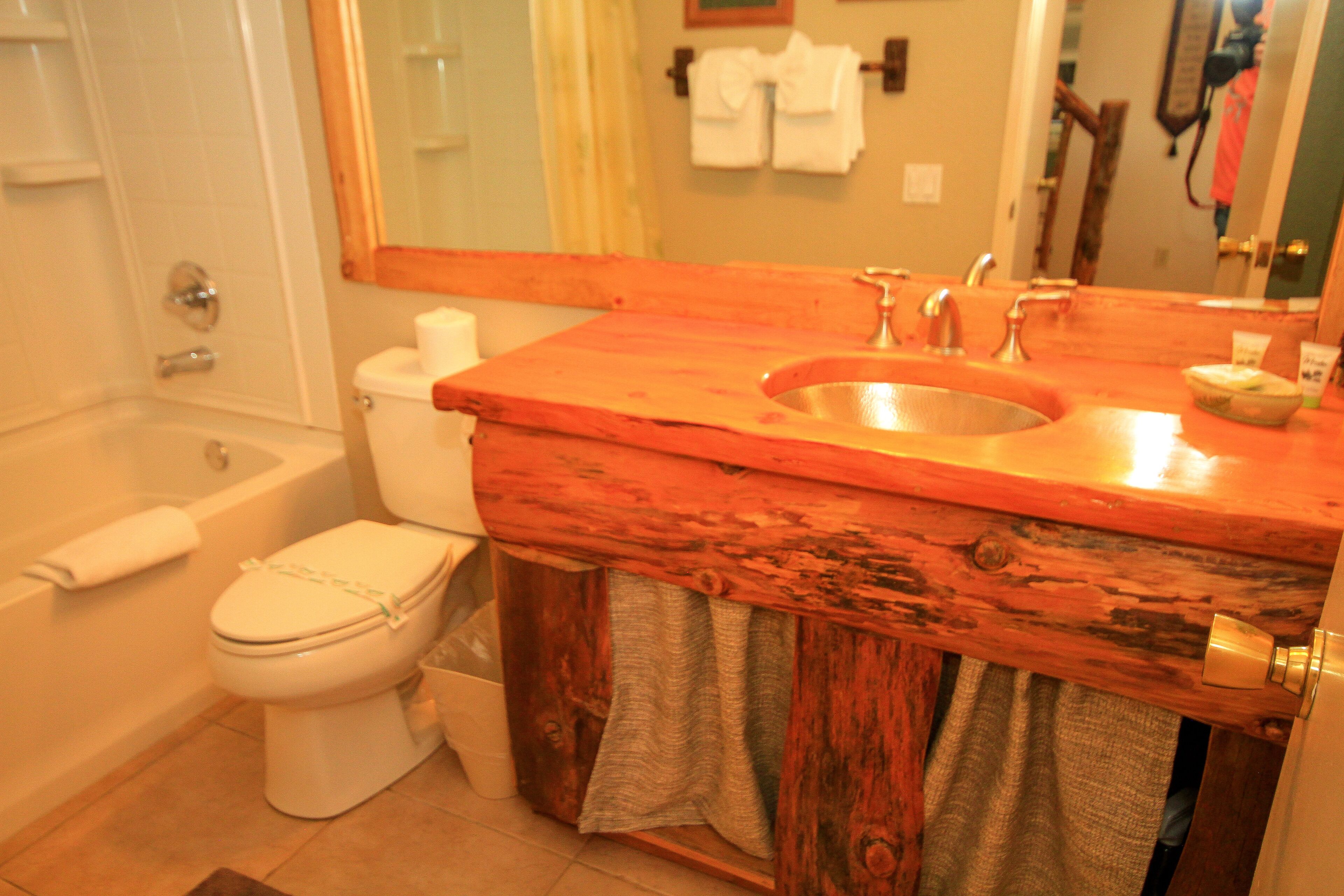 Une salle de bain avec un meuble-lavabo en bois, un évier et des toilettes.