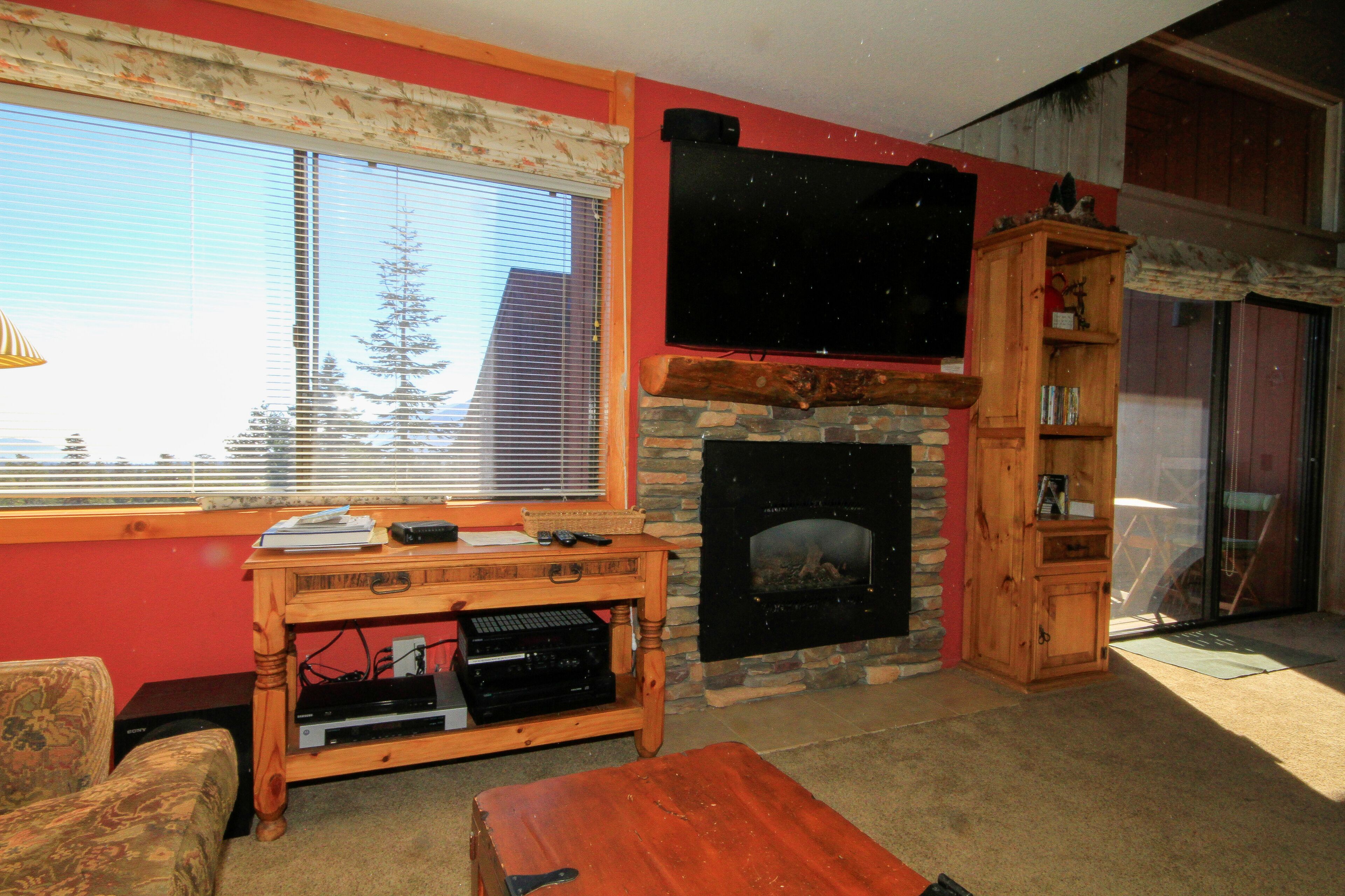 A living room with a fireplace, a television mounted above it, a wooden coffee table, and a couch.
