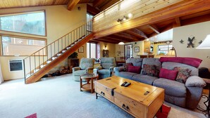 A spacious living room with a wooden staircase, a large sofa set, and a wooden coffee table. - Mountain Rustic, Spacious. Washer/Dryer, On-site Pool & Near Trails/Kids Park (Mammoth Lakes)