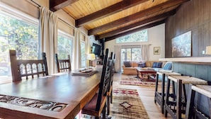 Amplia sala de estar con mesa de comedor de madera, un sofá y un televisor.