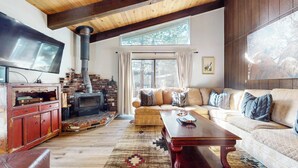 Una sala de estar acogedora con chimenea de ladrillo, televisor, sofá y mesa de centro.