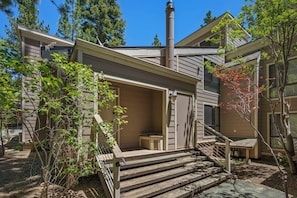 A two-story house with a chimney, a covered porch, and a small outdoor seating area. - 214 Forest Pine | 4BR/2BA Incline Village | Pool (Incline Village)