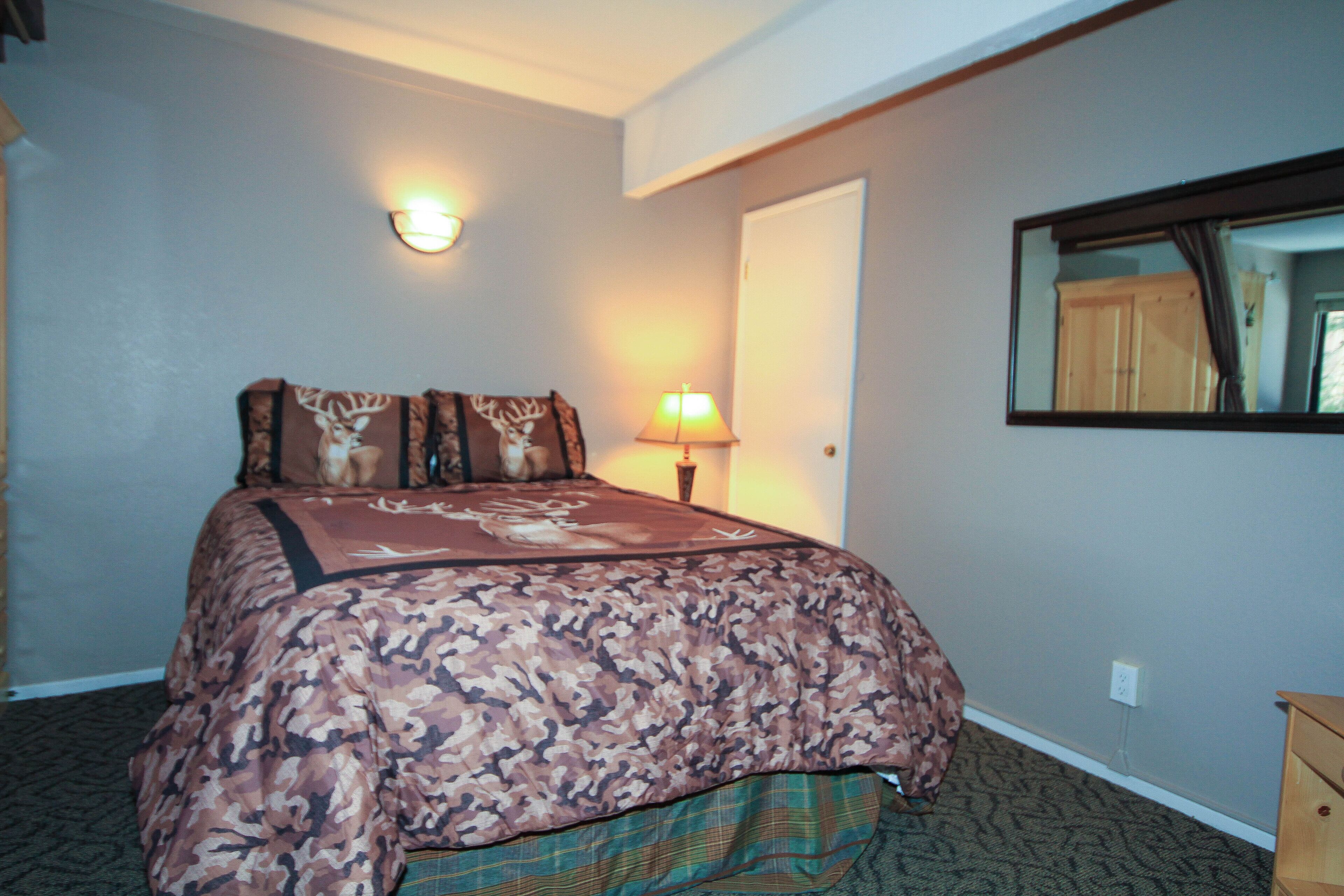 A hotel room with a bed, a nightstand, a lamp, and a mirror.