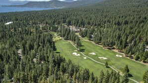 A golf course surrounded by dense forest with a lake and mountains in the background. - 206 Nadine | 3BR/2.5BA Incline Village | Fireplace & Patio (Incline Village)