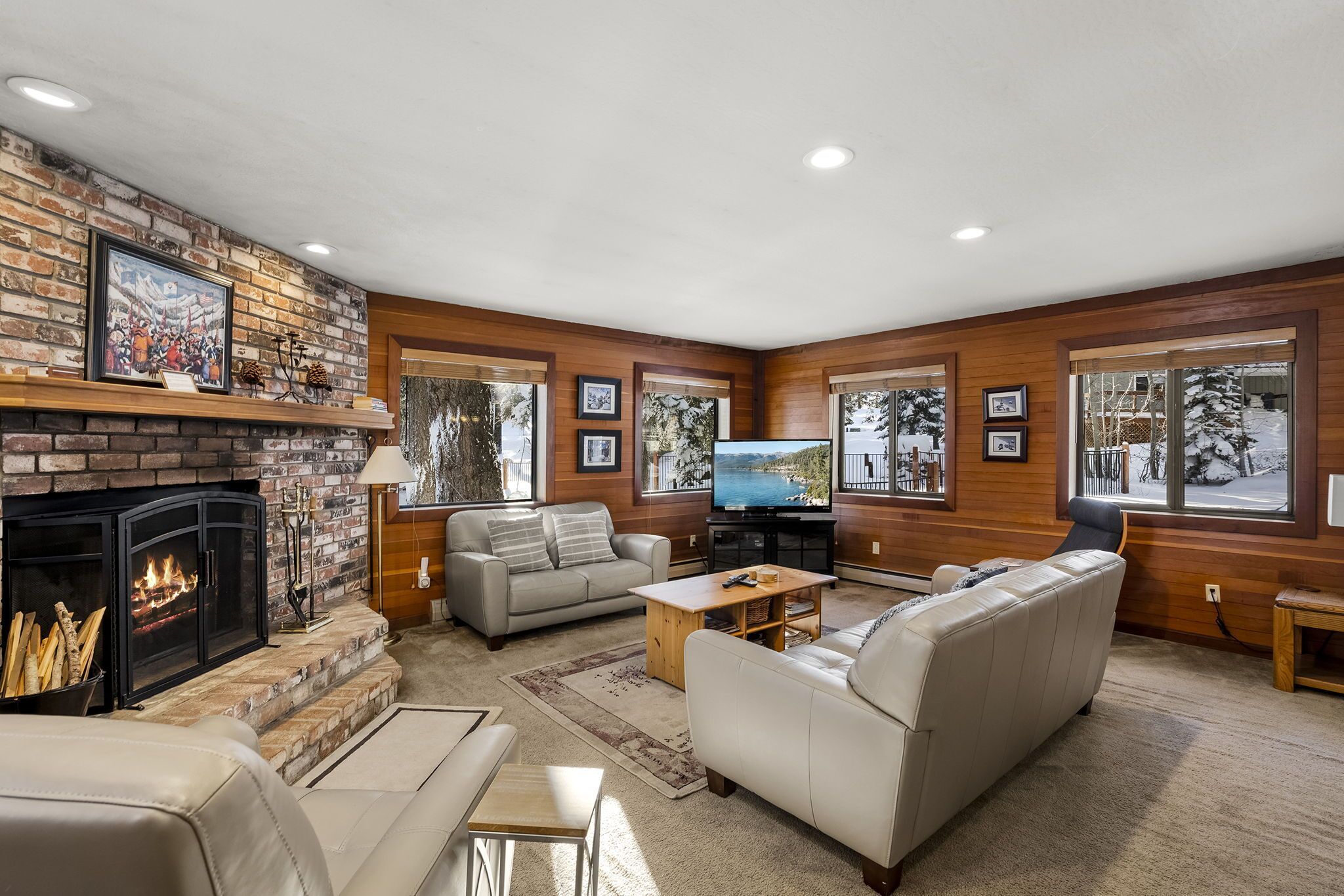 A cozy living room with a fireplace, comfortable seating, and large windows.