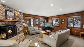 A cozy living room with a fireplace, comfortable seating, and large windows. - 206 Nadine | 3BR/2.5BA Incline Village | Fireplace & Patio (Incline Village)