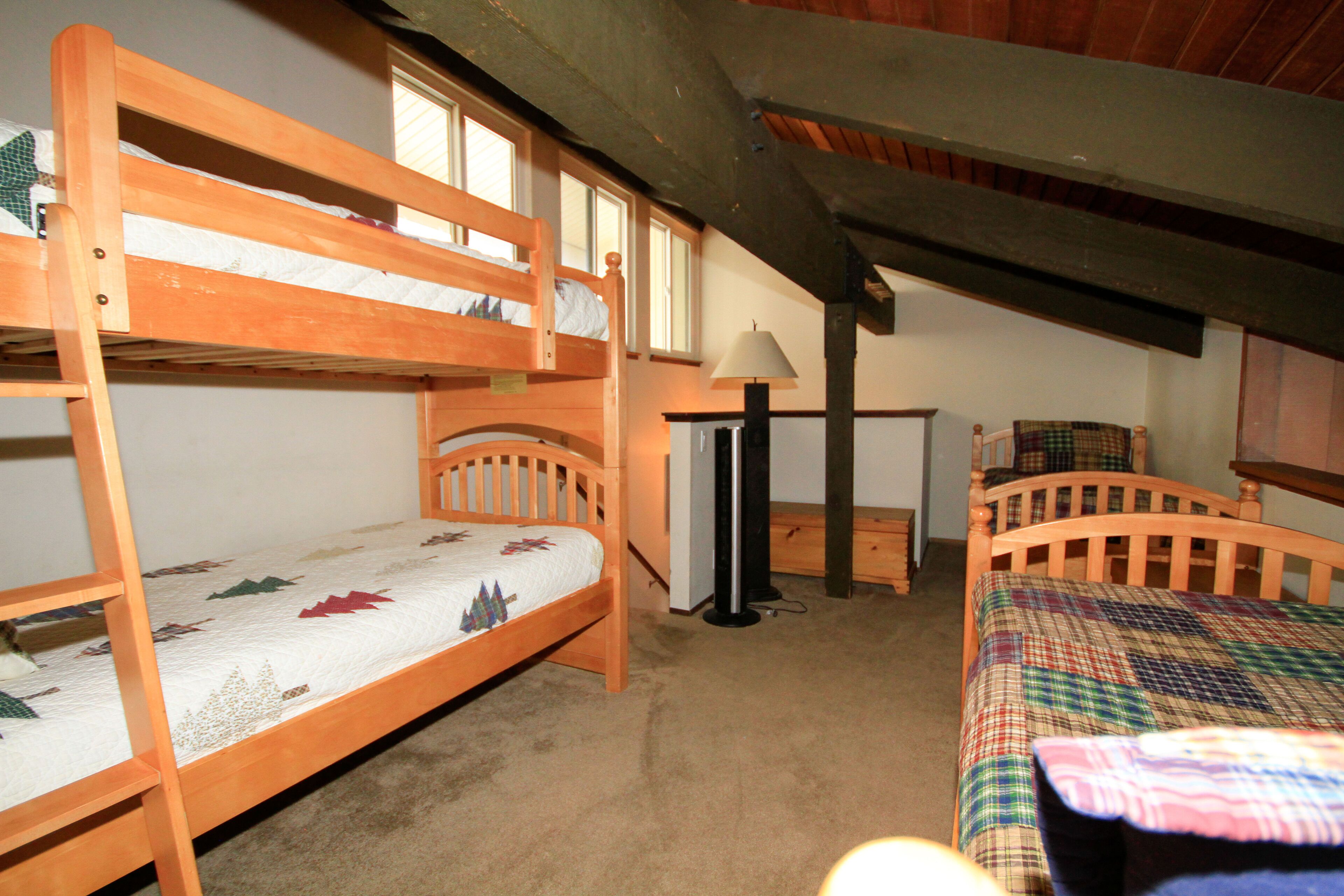 A room with two bunk beds, a desk, and a chair.