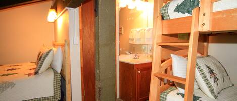 A bunk bed room with a wooden headboard, a bedside table, and a mirror.