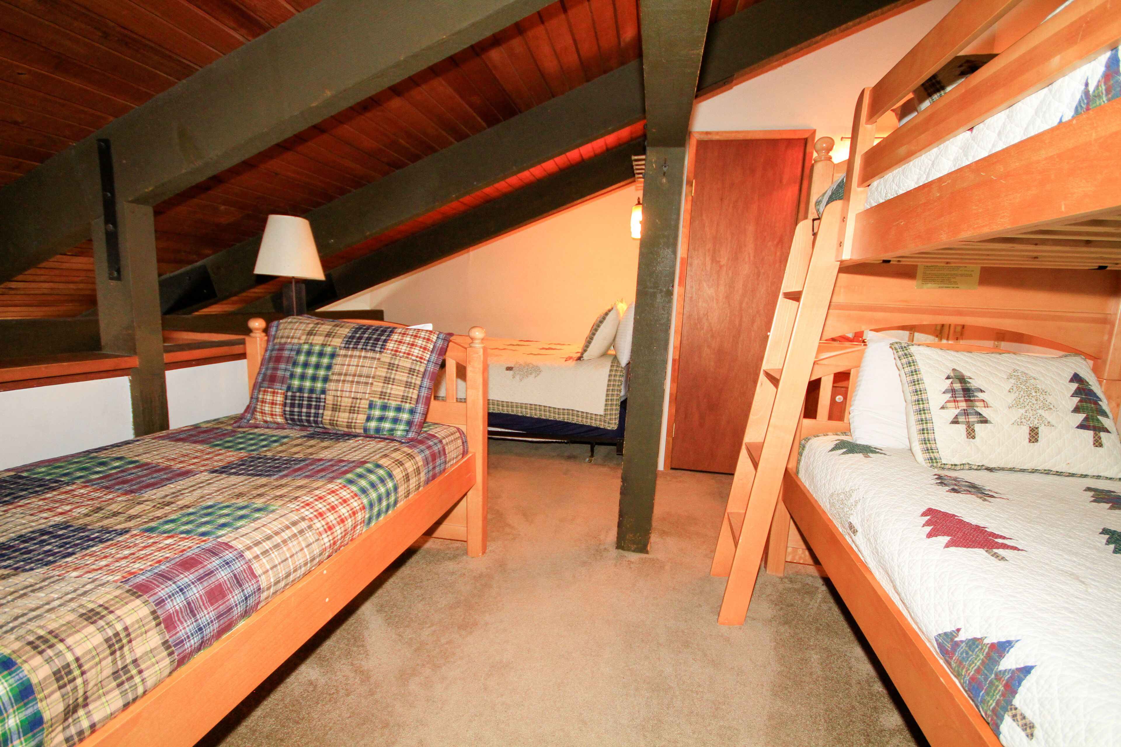 A room with two wooden bunk beds, a single bed, and a lamp.