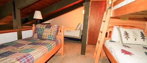 A room with two wooden bunk beds, a single bed, and a lamp.