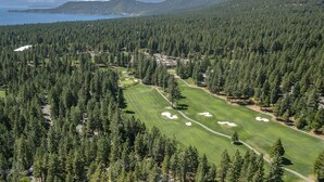 A golf course surrounded by dense forest and mountains.