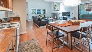 A modern kitchen with a built-in stove, wooden cabinets, and a dining area with a table and chairs.