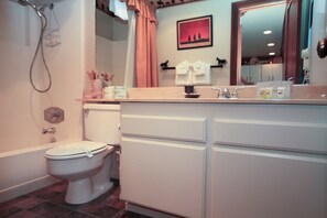 A bathroom with a toilet, bathtub, and a vanity with a mirror. - Mammoth Ski & Racquet Club #67- (Mammoth Lakes)