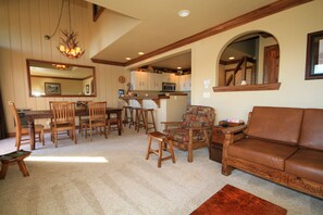 A spacious living room with a brown leather sofa, wooden chairs, a dining table, and a kitchen area in the background. - Mammoth Ski & Racquet Club #67- (Mammoth Lakes)