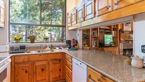 A kitchen with wooden cabinets, granite countertops, a dishwasher, a coffee maker, and a television.