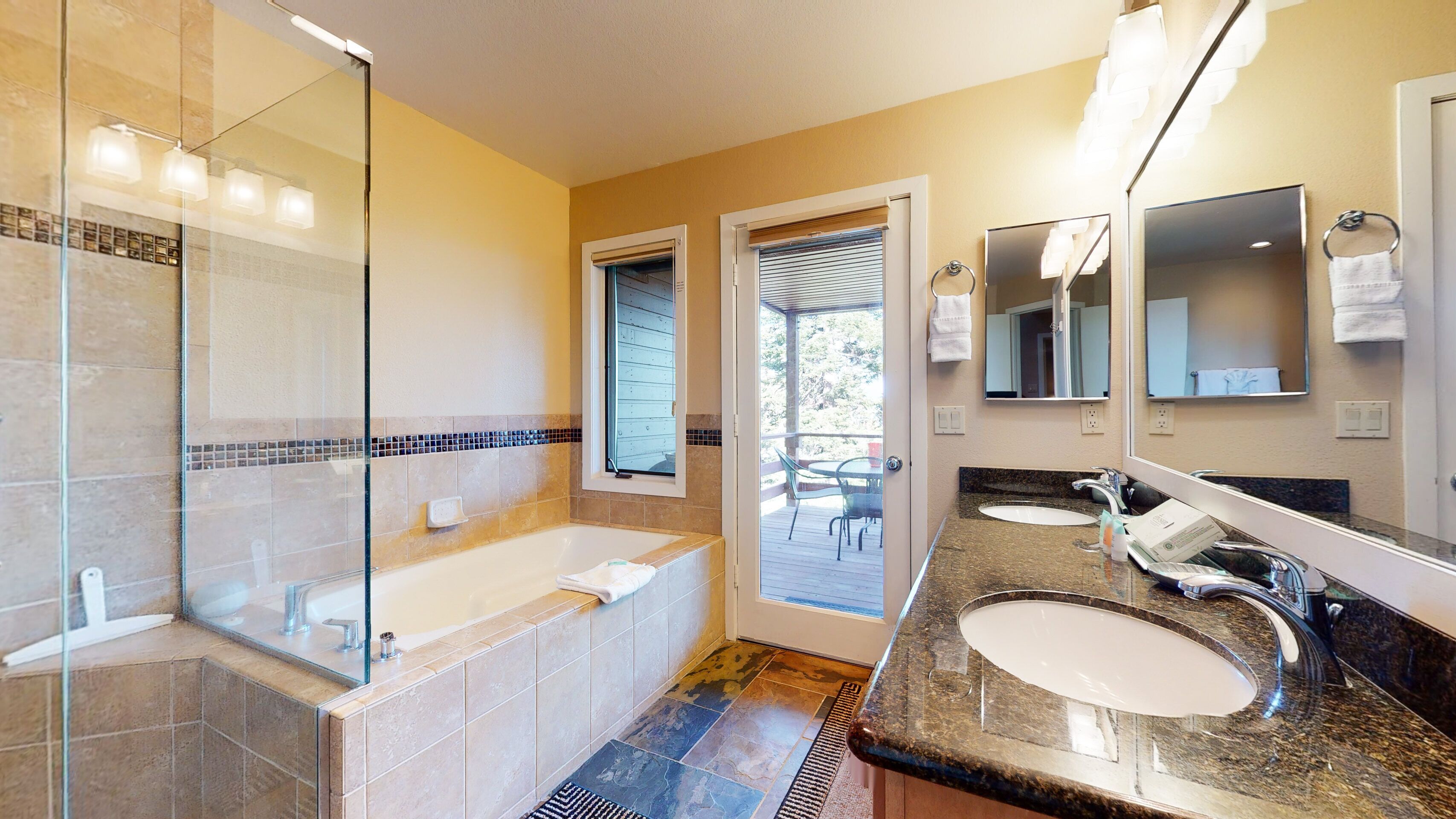 A modern bathroom with a glass shower enclosure, a bathtub, and two sinks.