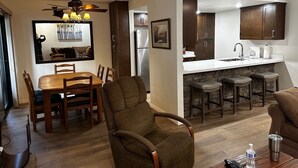 Een moderne keuken met een centraal eiland, een houten eettafel en barstoelen.