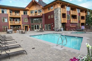 A hotel with a pool area, outdoor seating, and a stone facade.