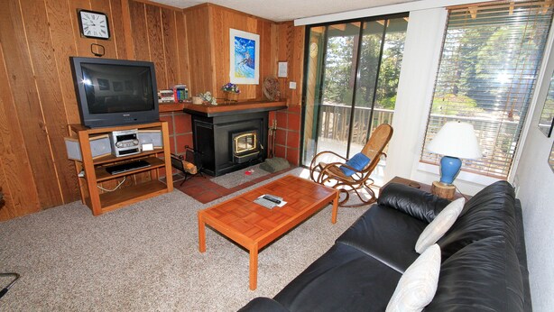 Una sala de estar con chimenea, televisor, sofá y sillón.