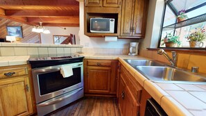 Enjoy cooking in this well-equipped kitchen with a stainless steel range hood, microwave, and modern sink.