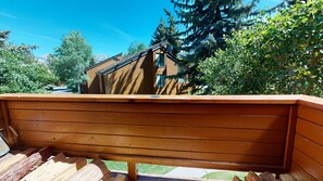 A wooden bench with a view of a house and trees.
