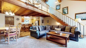 A spacious living area with a high ceiling, a staircase, and a dining area.