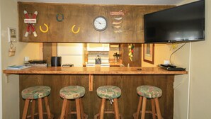 Een bar met houten krukken, een klok en een aan de muur bevestigde televisie.