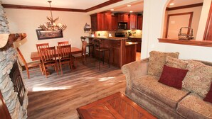A spacious living area with a wooden dining table, chairs, a sofa, and a kitchen in the background. - Mammoth Ski & Racquet Club #34 (Mammoth Lakes)