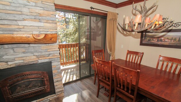A dining area with a stone fireplace, wooden dining table, and chairs. - Mammoth Ski & Racquet Club #34 (Mammoth Lakes)
