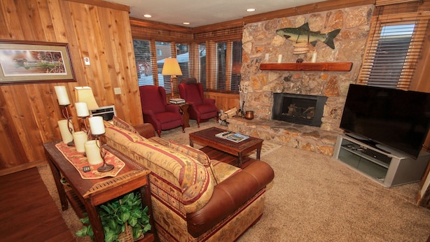 A cozy living room with a stone fireplace, leather sofa, and wooden walls. - Mountainback #49, Den (Mammoth Lakes)