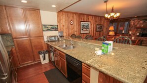 A kitchen with wooden cabinets, granite countertops, a dishwasher, and a sink. - Mountainback #49, Den (Mammoth Lakes)