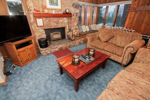 A cozy living room with a stone fireplace, a television, and a comfortable sofa.