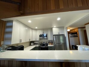 Una cocina moderna con armarios blancos, electrodomésticos de acero inoxidable y una isla central.