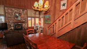 A wooden interior with a fireplace, a dining table, and a staircase. - Mountainback #105, Loft, Den (Mammoth Lakes)