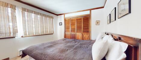 Un dormitorio con una cama grande, cabecera de madera y un armario con espejo.