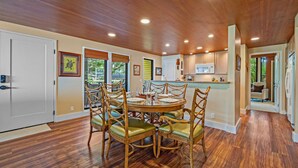 Un espace repas avec une table ronde et des chaises, un plancher en bois et des spots encastrés au plafond.