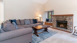 A living room with a stone fireplace, a sofa, a coffee table, and a lamp. - 47 McCloud | 3BR/3BA Incline Village, Hot Tub (Incline Village)