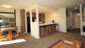 A modern kitchen with a central island, bar stools, and a dining table with chairs. - Discovery 4 #135 1 Bedroom 1 Bath (Mammoth Lakes)