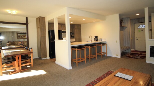 A modern kitchen with a central island, bar stools, and a dining table with chairs. - Discovery 4 #135 1 Bedroom 1 Bath (Mammoth Lakes)