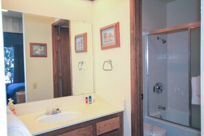 Une salle de bain équipée d’un lavabo, d’un miroir, de tableaux encadrés et d’un espace douche.