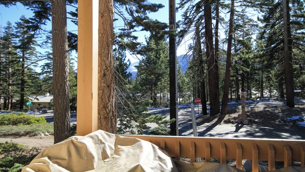 A covered outdoor area with a bench, surrounded by tall trees and a road with a stop sign. - Discovery 4 #135 1 Bedroom 1 Bath (Mammoth Lakes)