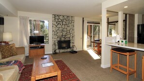 A living room with a stone fireplace, a television, a sofa, and a coffee table. - Discovery 4 #135 1 Bedroom 1 Bath (Mammoth Lakes)
