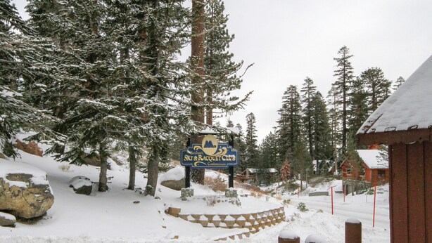 A snow-covered landscape with a sign for the Ski & Racquet Club. - Mammoth Ski & Racquet Club #25 (Mammoth Lakes)