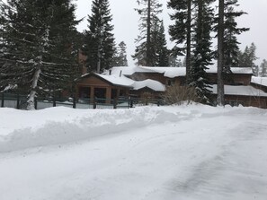 A snow-covered lodge with a wooden exterior, surrounded by tall evergreen trees. - Mountainback #34, Corner (Mammoth Lakes)