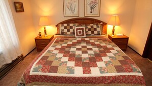 A neatly made bed with a floral quilt, two bedside lamps, and framed floral artwork on the wall. - Discovery 4 #128, Loft - Pet Friendly (Mammoth Lakes)