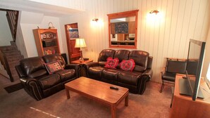 A living room with a leather sofa, a wooden coffee table, a bookshelf, and a desk with a computer. - Discovery 4 #128, Loft - Pet Friendly (Mammoth Lakes)